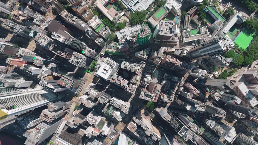 An extreme aerial overhead view pans down over a densely packed urban area with numerous tall buildings and streets below