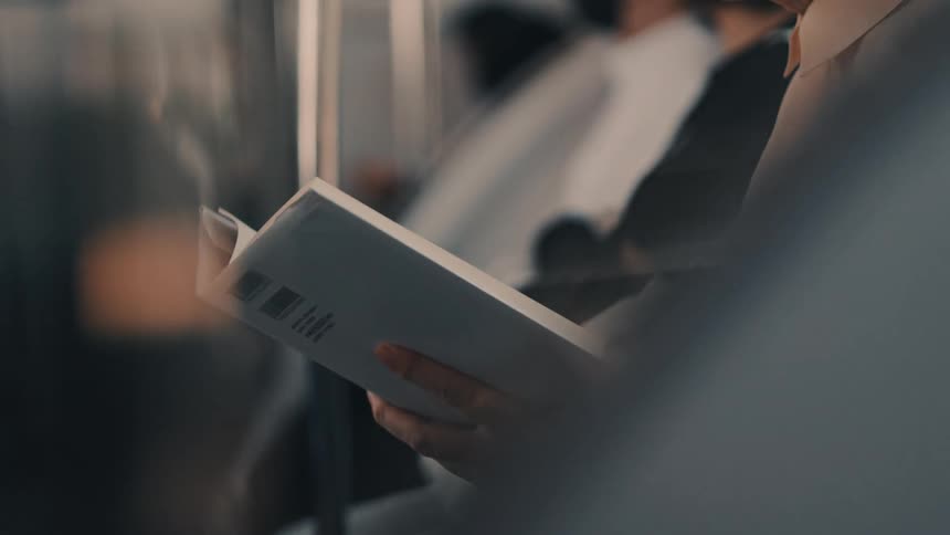 A person reads a book during a crowded commute on a metro train