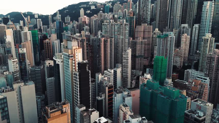 An aerial view pans over a densely packed city of numerous high rise buildings in a concentrated urban area