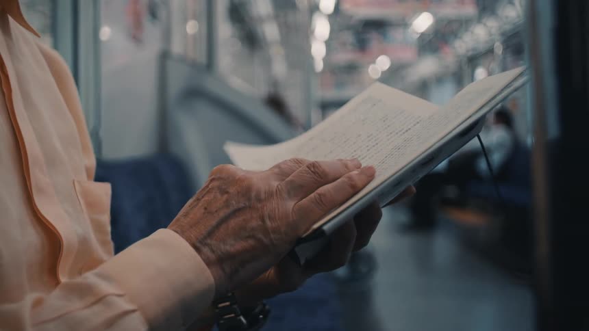 Hand flipping through an open book inside a train carriage
