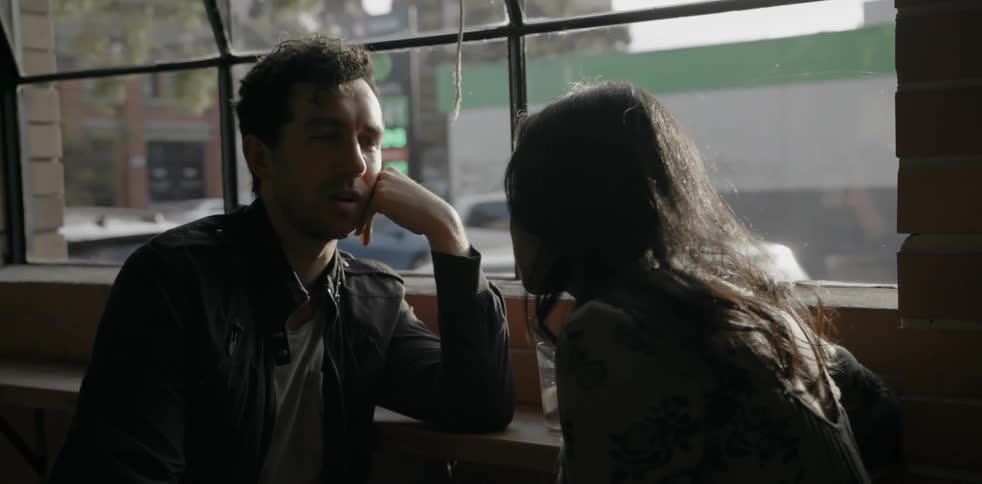 A man and a woman sitting by a window in a cafe and chatting