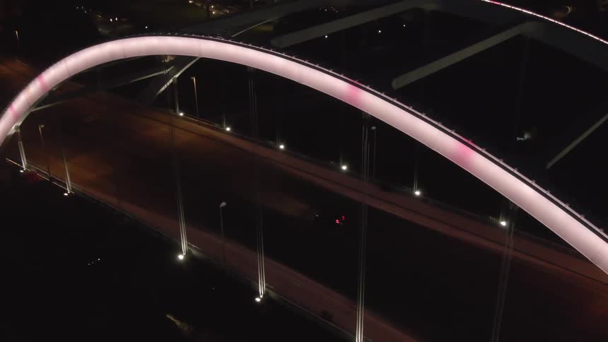 A car drives over a bridge lit up at night
