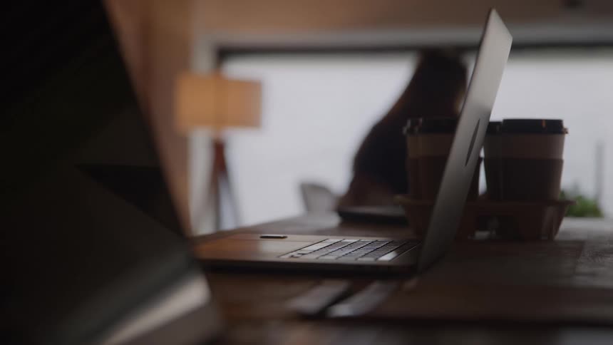Open laptops on a table with coffee cups in the background