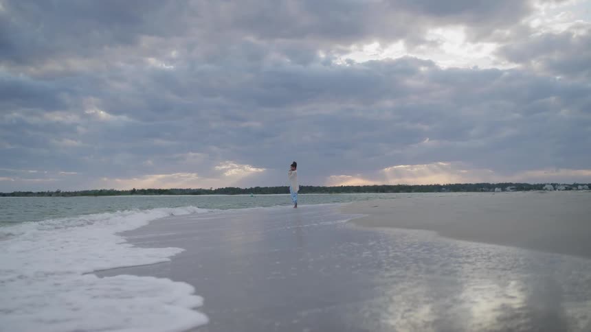 The woman stands in the water on the shore