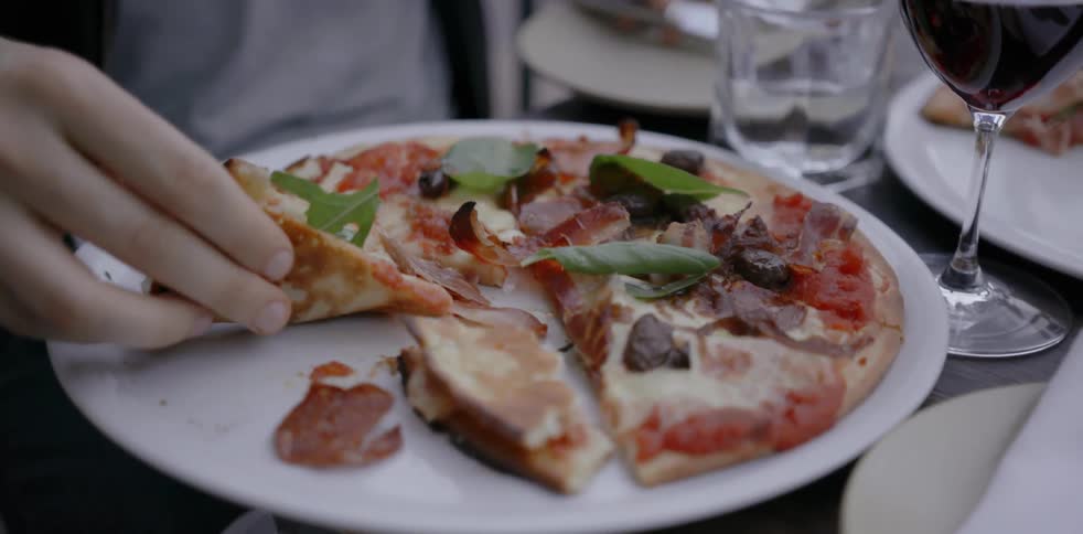 Person picking up slice of pizza from plate