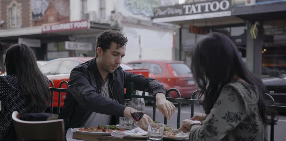 A man and woman dine at an outdoor table in a city
