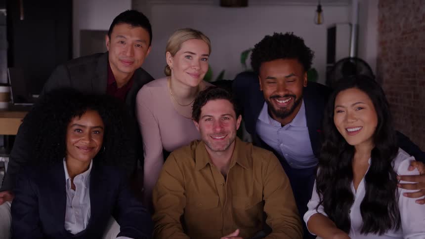 Small group of male and female people posing and smiling at an office indoors