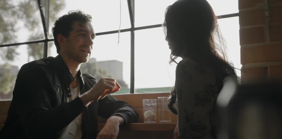 A man and woman sit at a small table and chat