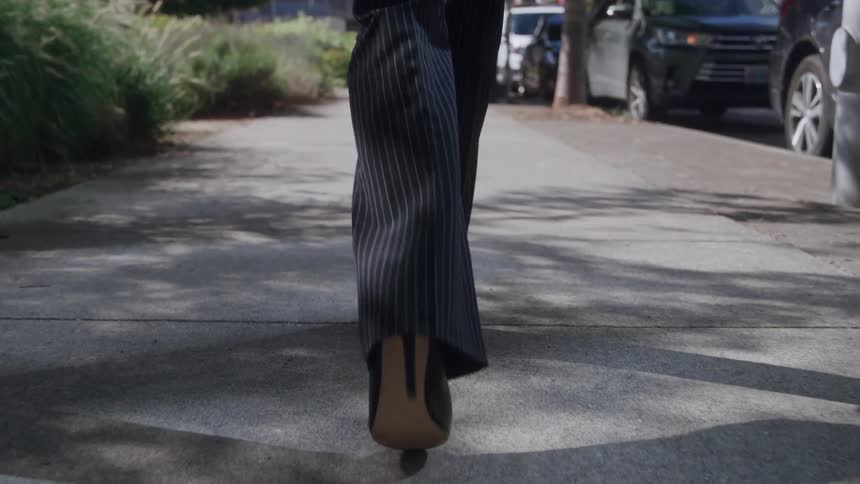 High heels walking along a shaded sidewalk