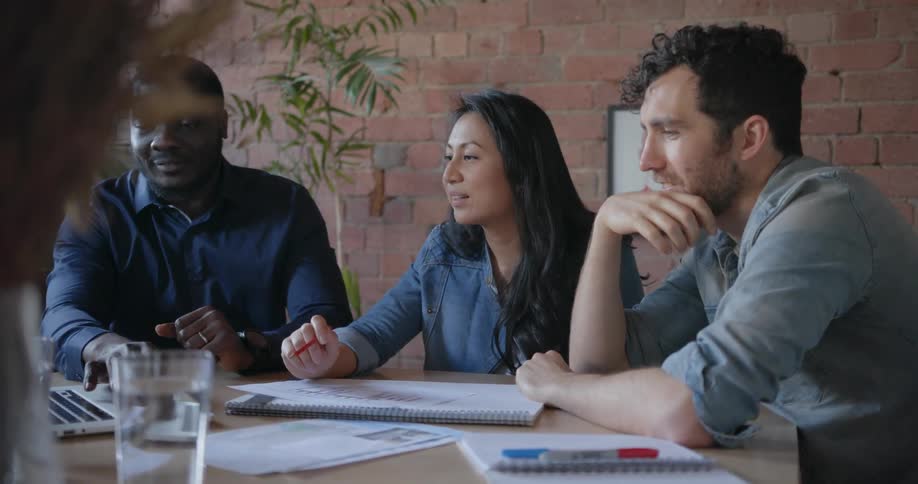 Three people talk in a conference room together