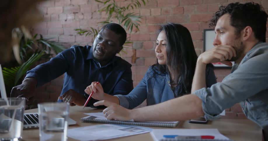 Office workers gather around a laptop and talk