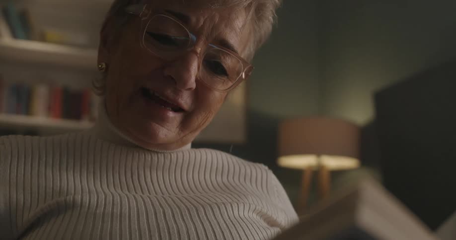 Elderly woman reading a book in an indoor setting