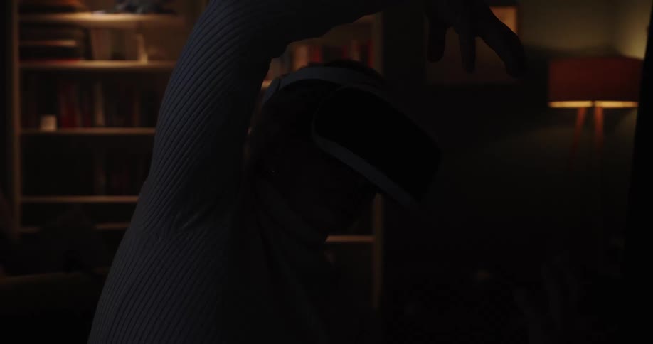 Woman using a virtual reality headset with arms raised in a room