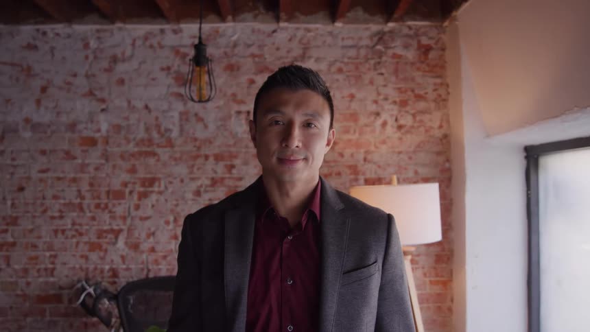 Man standing in front of an exposed brick wall in an indoor setting