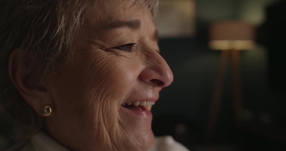 Elderly woman smiling in a side closeup indoors