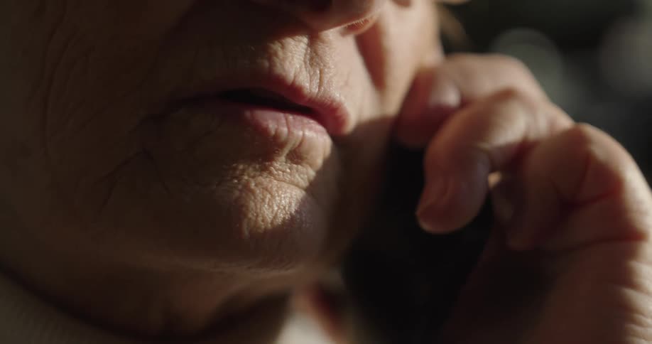 A close up of the mouth of an elderly woman talking on a cell phone