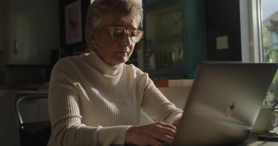 Woman sitting at a table typing on a laptop computer