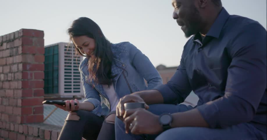 A man and woman talk on a rooftop