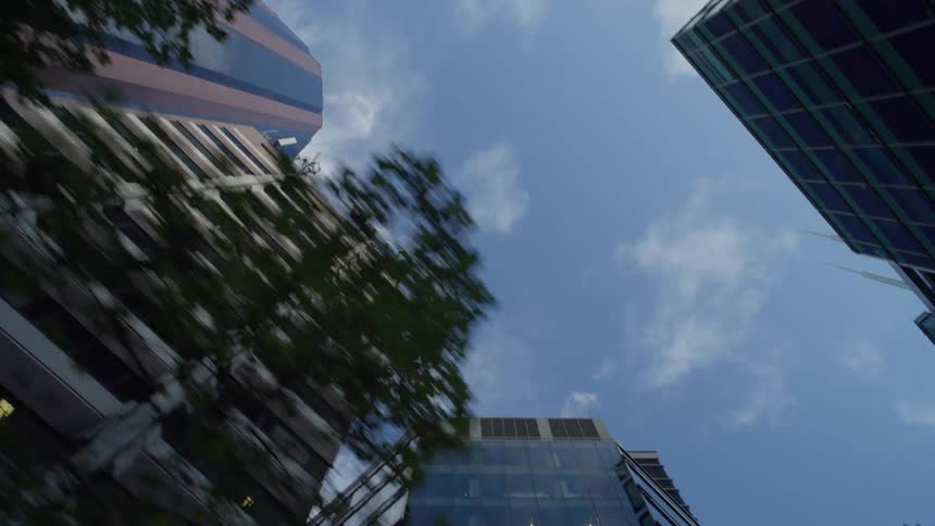 Tall buildings seen from below with blurred tree canopies around