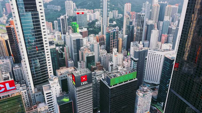 Aerial view of a metropolitan area with many skyscrapers next to a green hill outdoors during day time