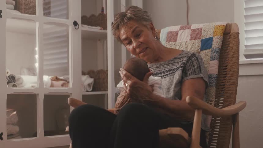 Elderly woman holding a baby in a rocking chair