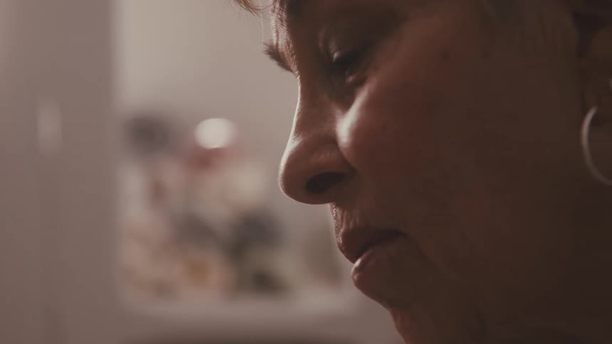 A close up of an older womans head rocking back and forth as she appears sad