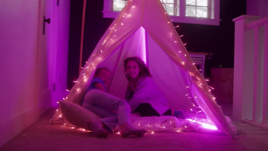 The two girls race and jump into the tent in the hallway