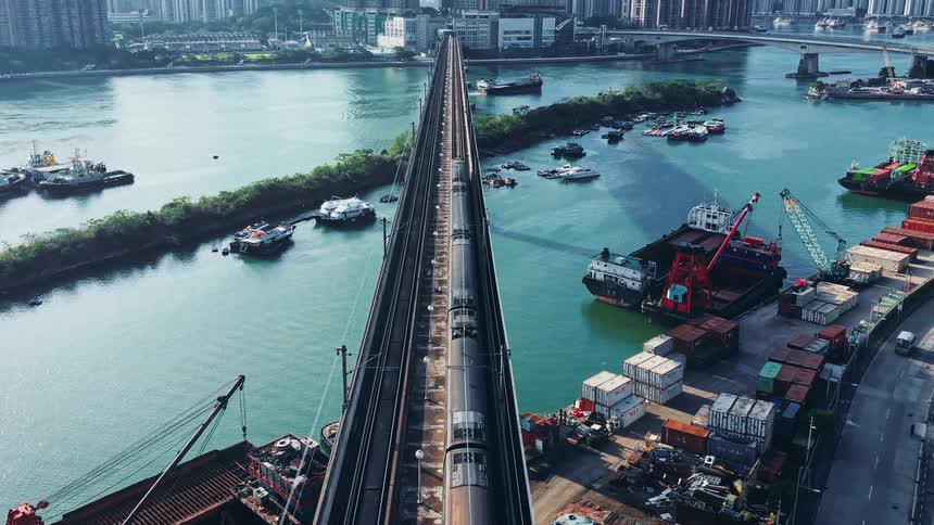An aerial view of a train going across a bridge into a city