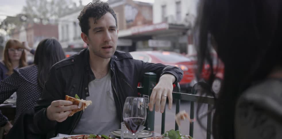 A man and woman eat and talk outside