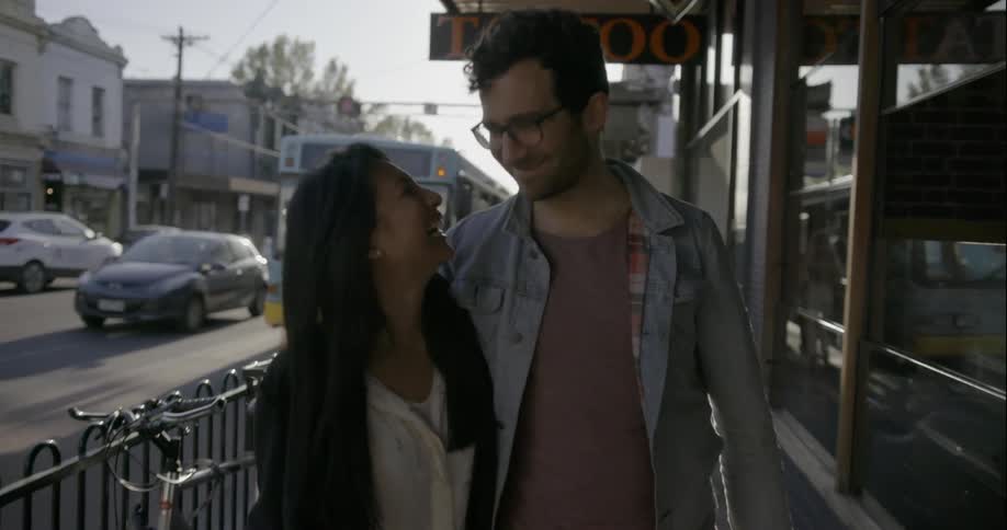 A man and woman walk down the street and kiss
