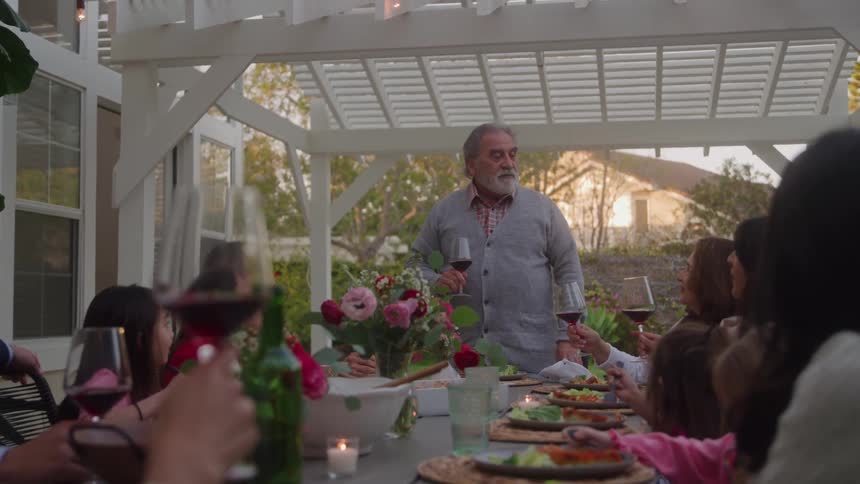 A man is giving a toast at a family dinner while the kids eat their food