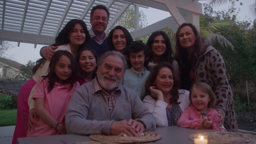 A large family with parents and kids pose for an outdoor picture under a gazebo