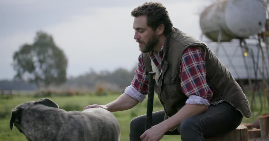 A man sits outside and pets a dog