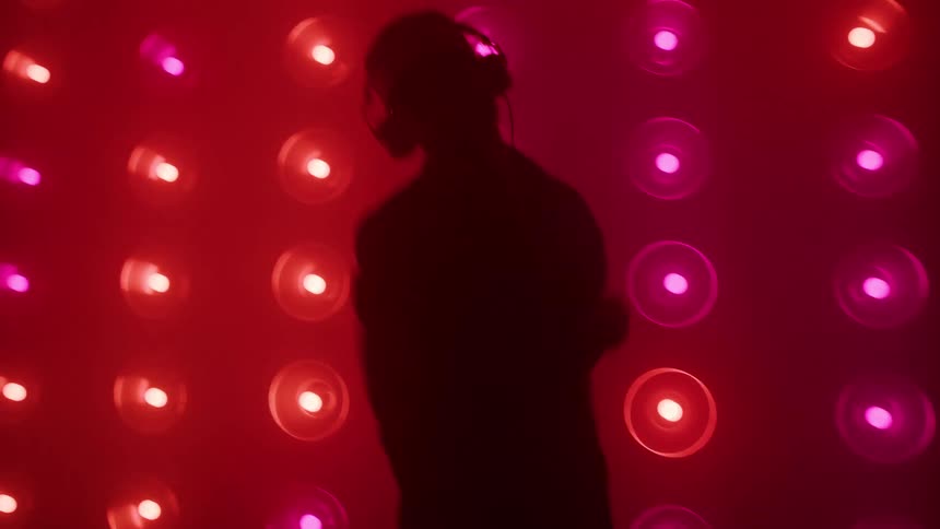 A man is dancing in front of a wall of lights