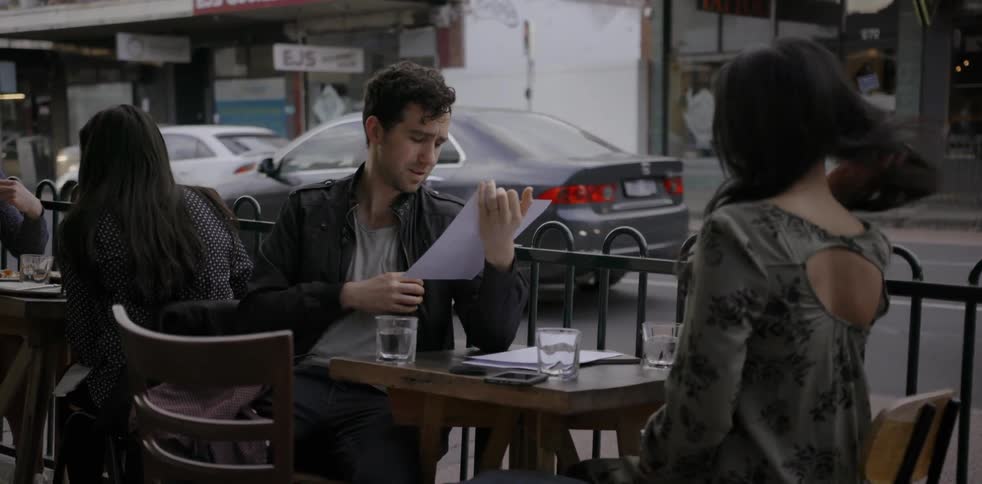 Two people are sitting at a table outside looking at menus