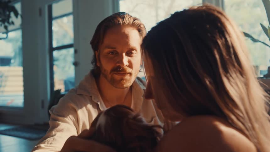 A man and woman are in a room petting and loving on a pet dog happily
