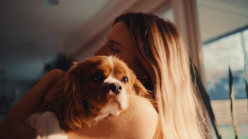 The woman is hugging and petting her dog