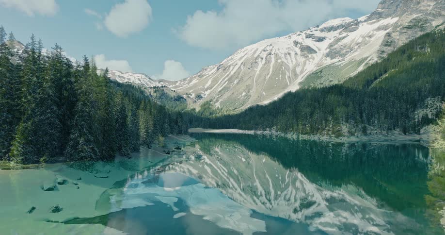 A seamless visual transition transforms a majestic mountain landscape from a cold snowy winter scene into a lush vibrant summer paradise with a crystalclear turquoise lake