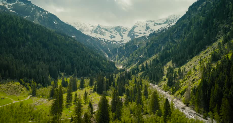 A mountain valley transitioning from a snowy winter landscape to a lush green summer scene