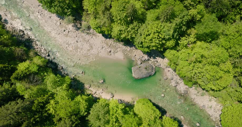 Clear river flows through dry dusty banks as it cuts through a forest