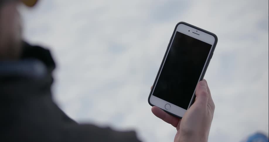 A man is using his cellphone as he stands outside
