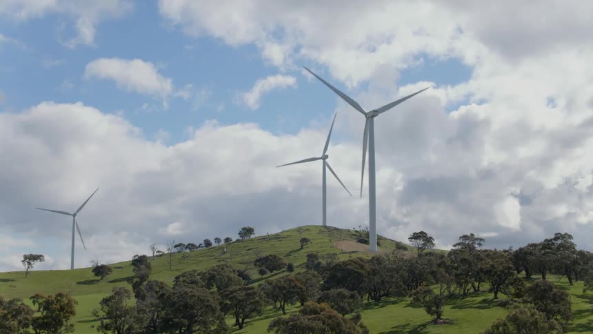 Wind turbines rotate atop a hill