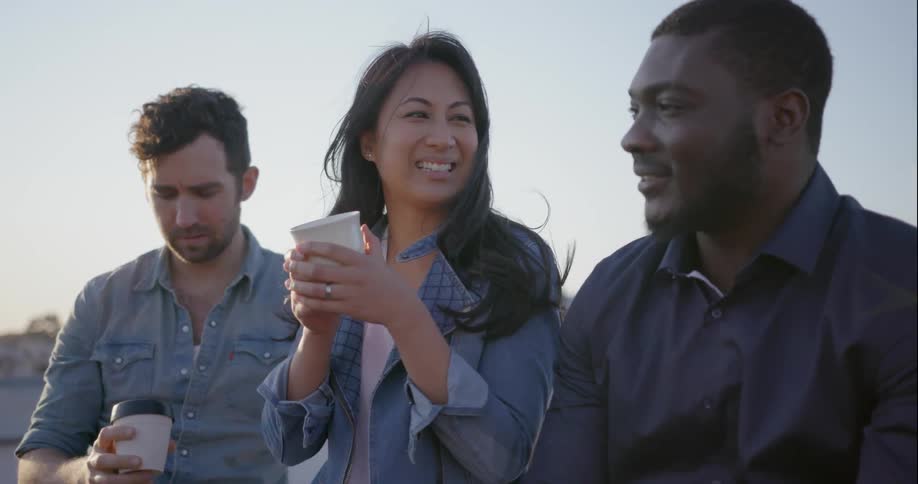 Group of people talking and drinking from cups outdoors