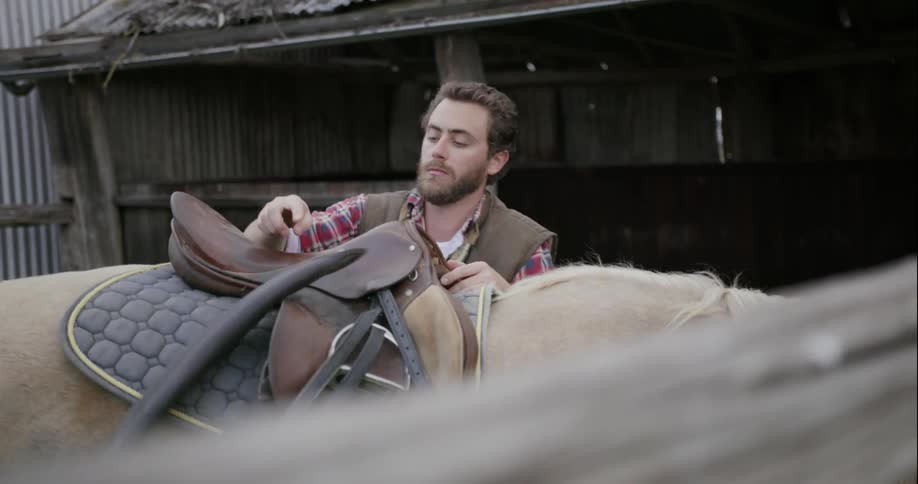 A man puts a saddle on a horse