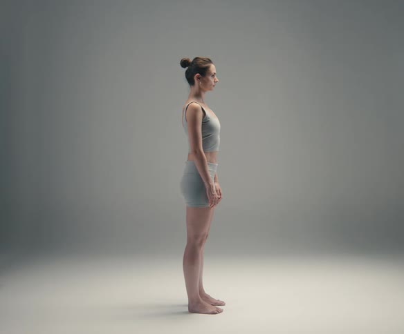 Woman in an upright position corrects her posture against a neutral background