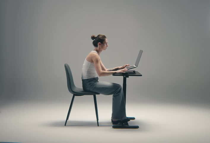 Woman sitting at a table typing on a laptop computer