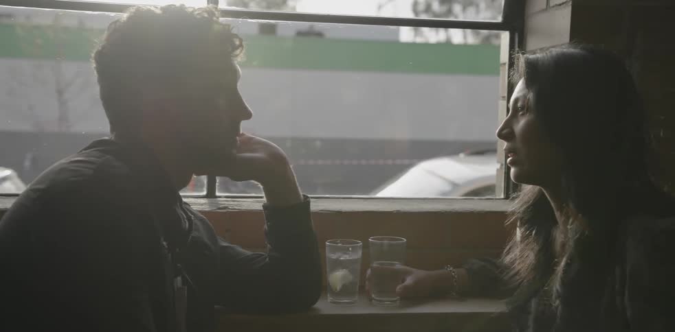 Two people sit in a restaurant talking