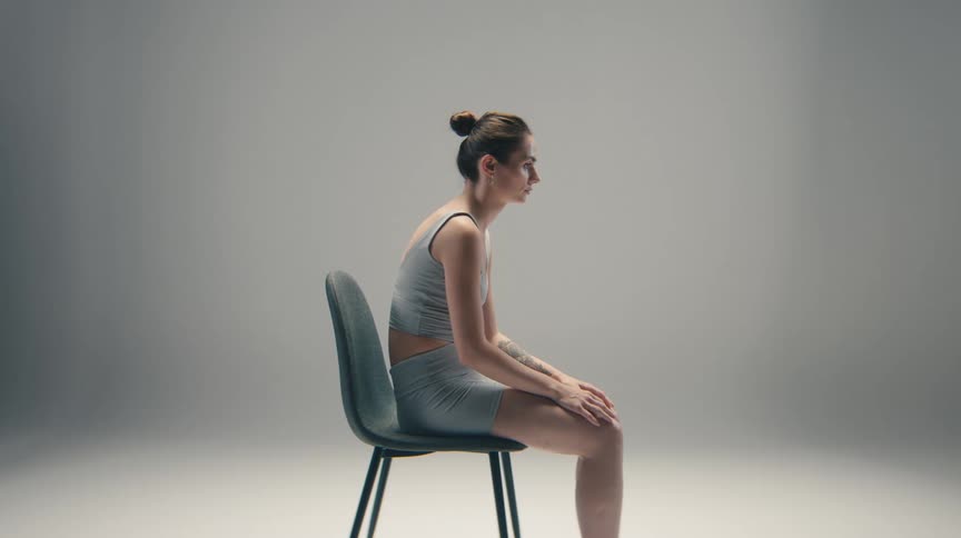 Woman seated in profile on a chair with a forwardleaning posture