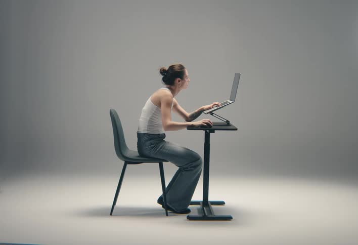Woman sitting at a table typing on a laptop computer