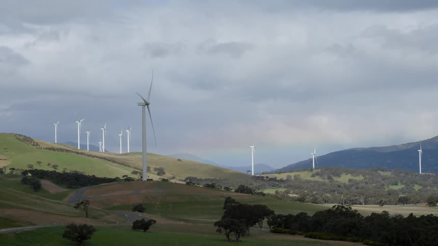 Wind turbines spin in a hilly area